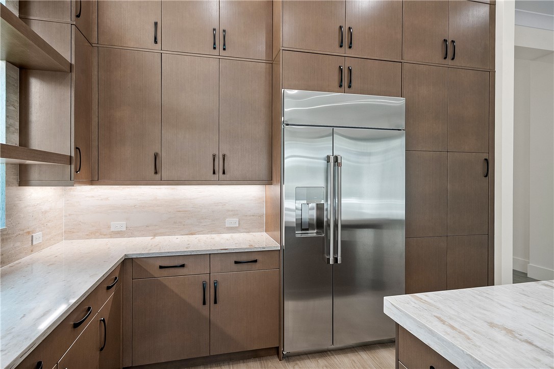 Kitchen featuring built in fridge, decorative backsplash, and light stone countertops