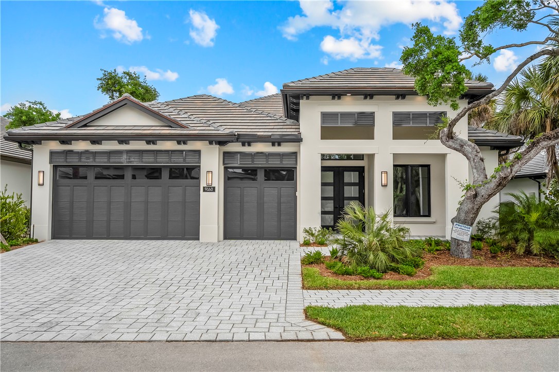 View of front facade with french doors, decorative driveway, an attached garage, and stucco siding