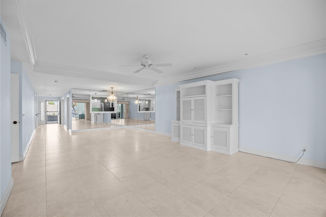Spacious interior featuring light-toned tile flooring, crown molding, and a ceiling fan