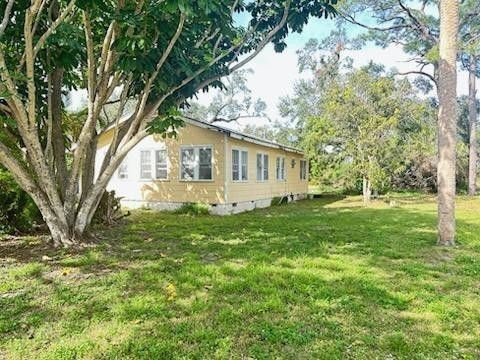 View of home's exterior with a lawn and crawl space