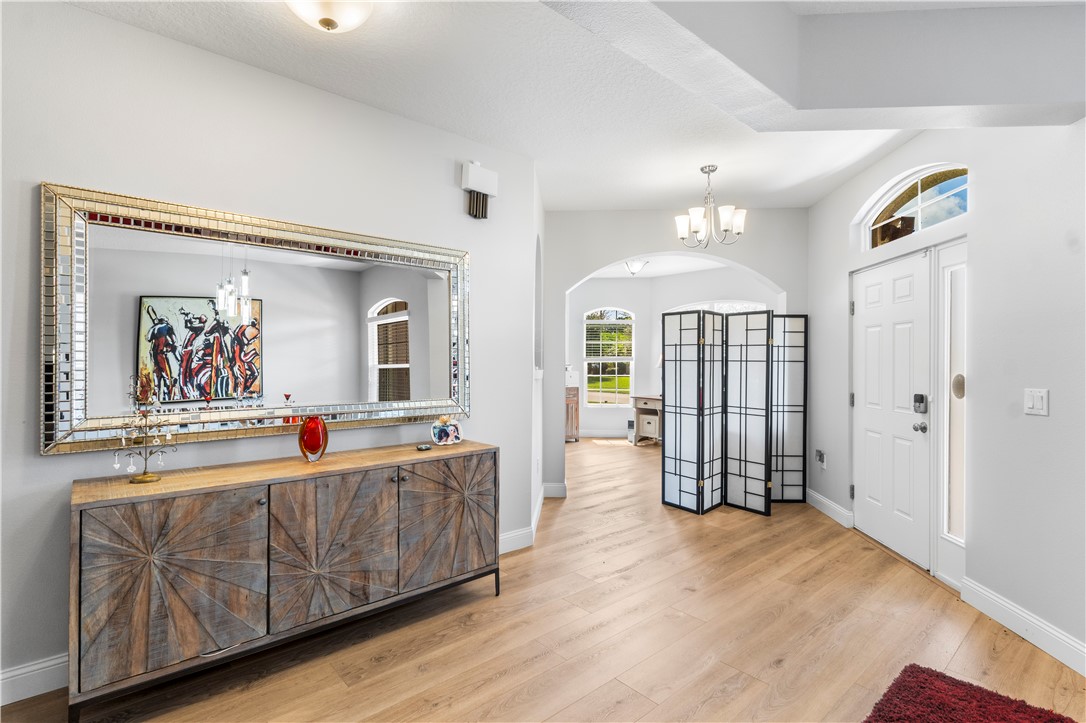 Recessed lighting, wood-finish flooring, arched entryway, transom window, and a paneled front door