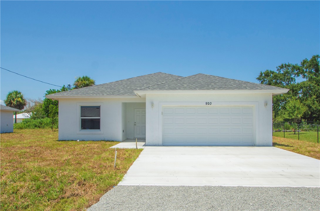 Single-story residence featuring a two-car garage, white stucco exterior, and a concrete driveway