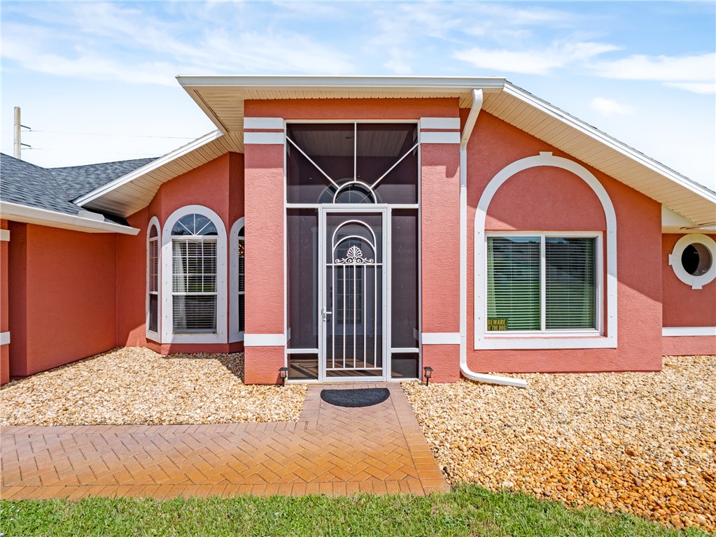 Stucco exterior with decorative arched windows and a screened entry
