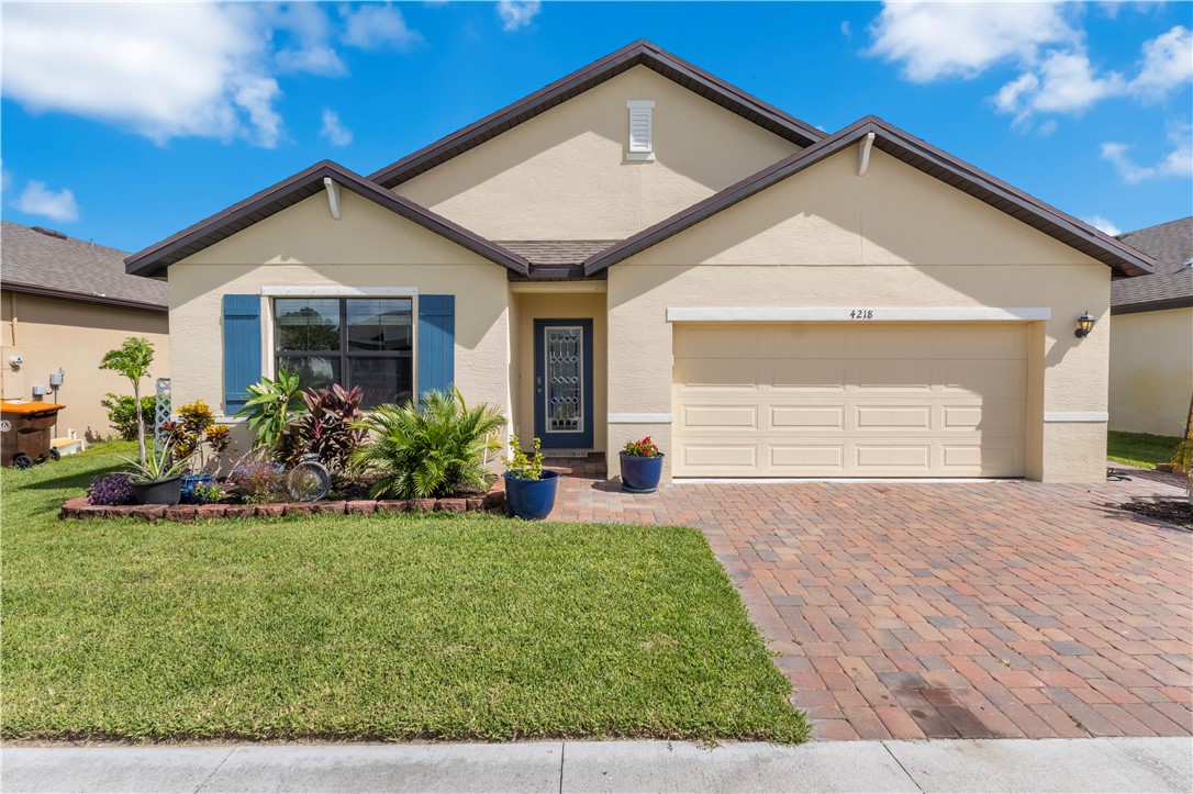Stucco exterior with a pitched roof, front entry door with decorative glass, and a paneled garage door