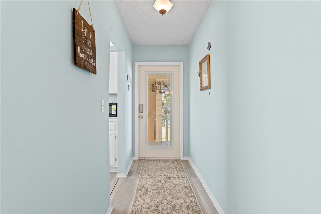 Entryway featuring light-toned walls, wood-finish flooring, and a glass-paneled entry door