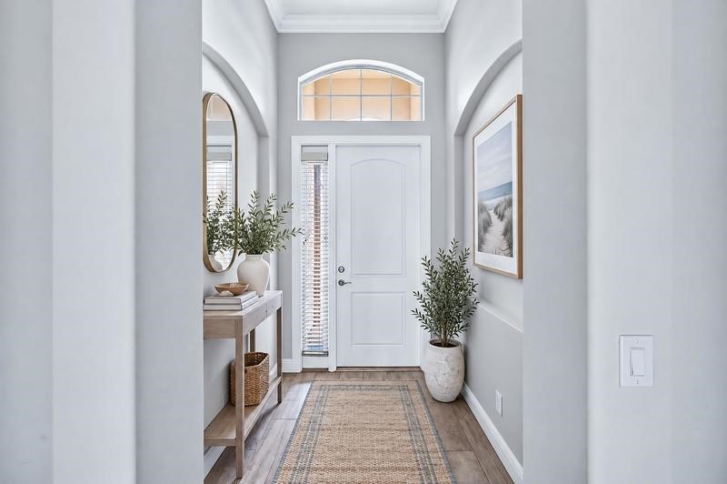 Entryway featuring wood-finish flooring, a white paneled door with an arched transom window, and arched wall openings