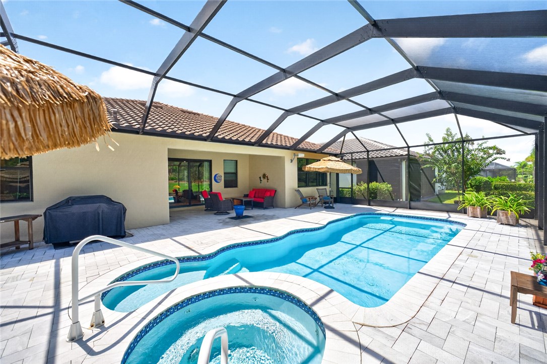 Screened patio featuring a swimming pool, integrated spa, and tile roofline