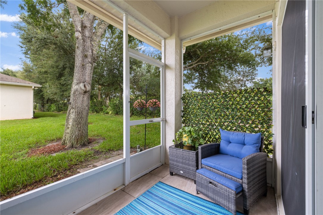 Screened outdoor living space featuring tiled flooring and a privacy hedge