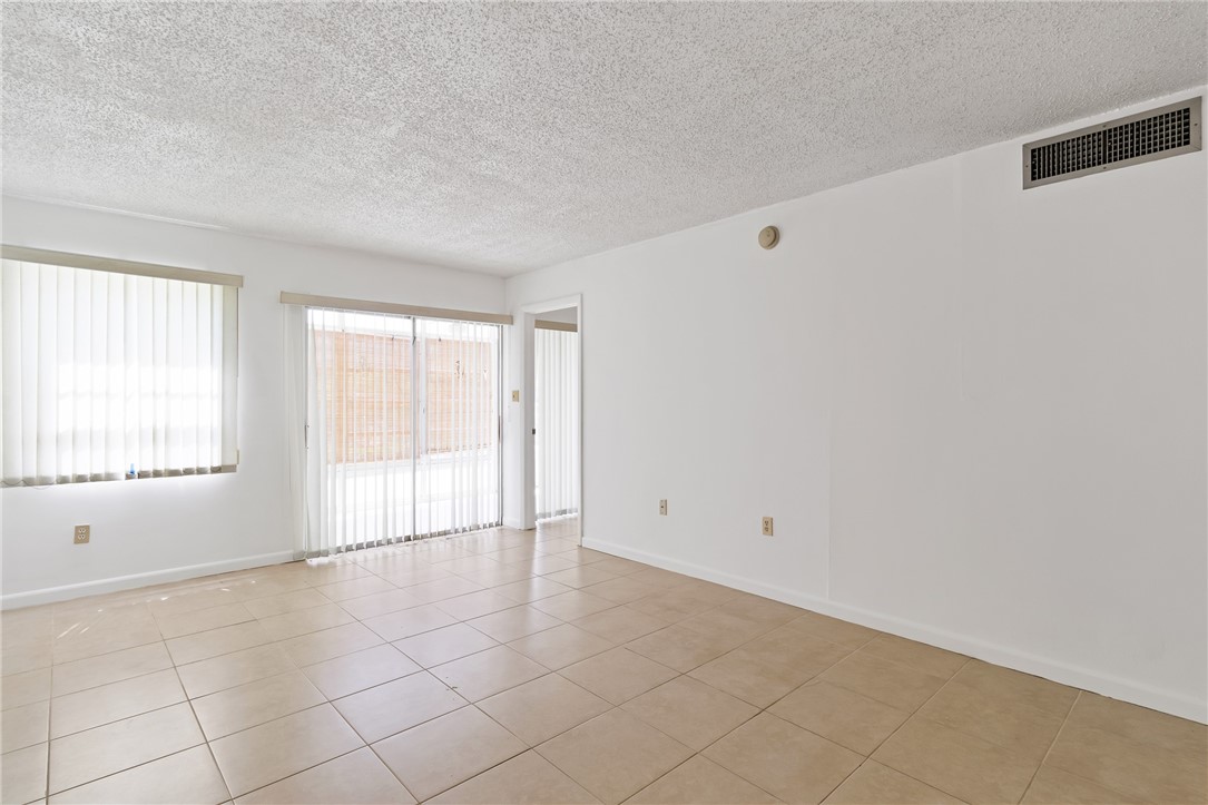 Ceramic tile flooring, white vertical blinds, and a sliding glass door