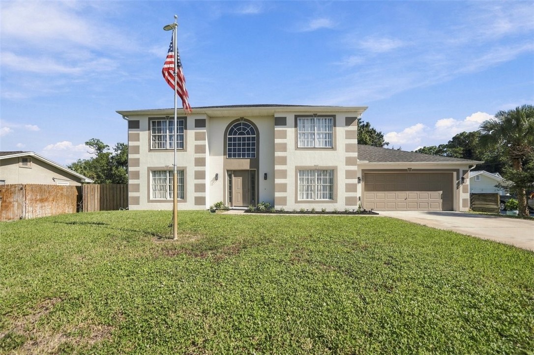Two-story stucco exterior with decorative trim, arched entry window, and an attached garage