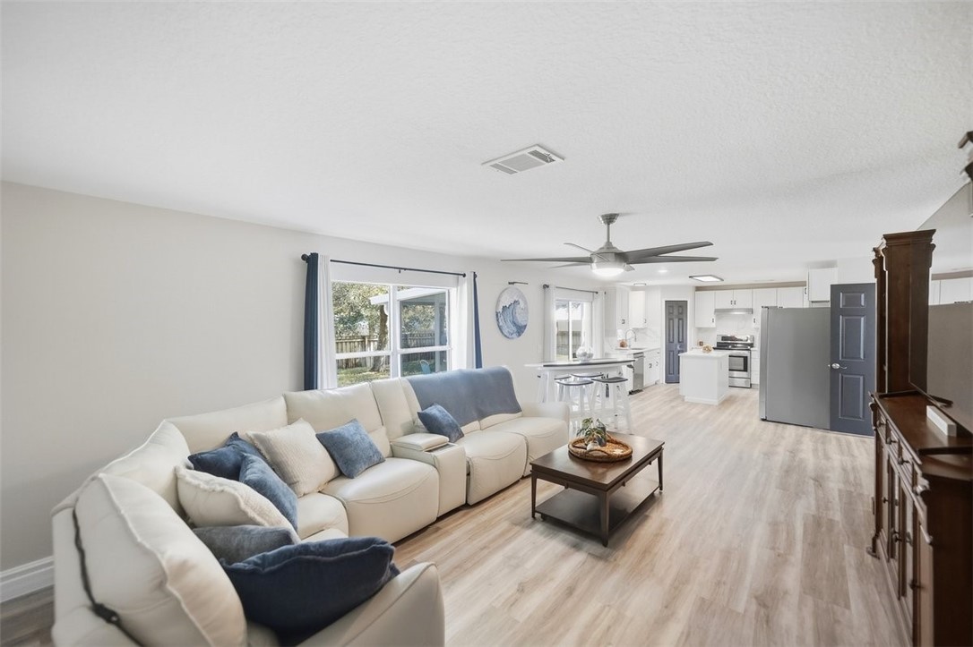 Open-concept living area with wood-finish flooring, a contemporary ceiling fan, and recessed lighting