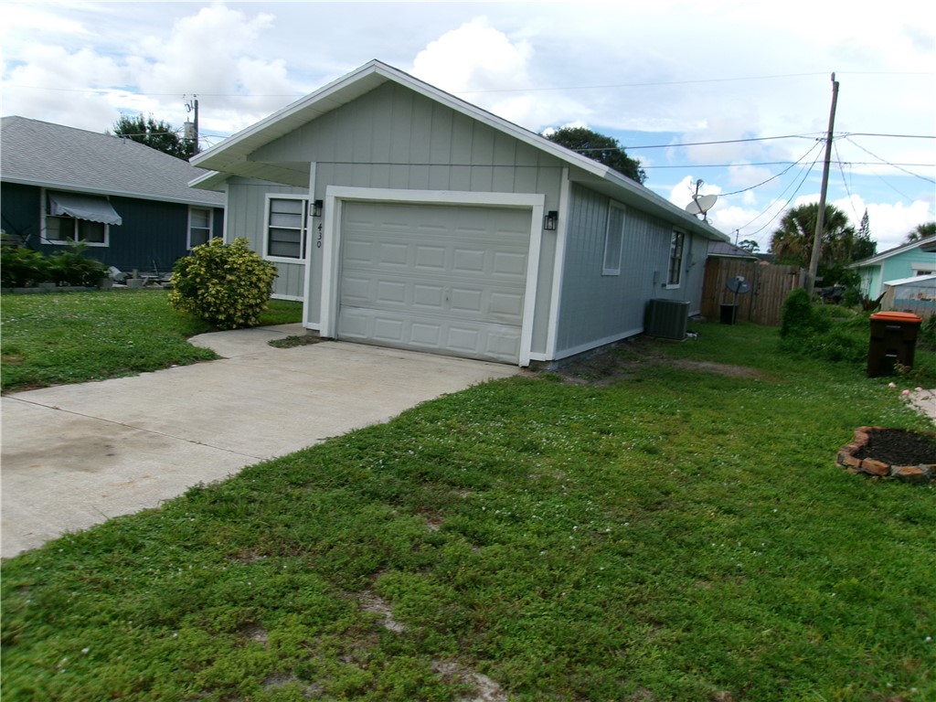 Single-story structure with light grey siding, an attached garage, and a concrete driveway