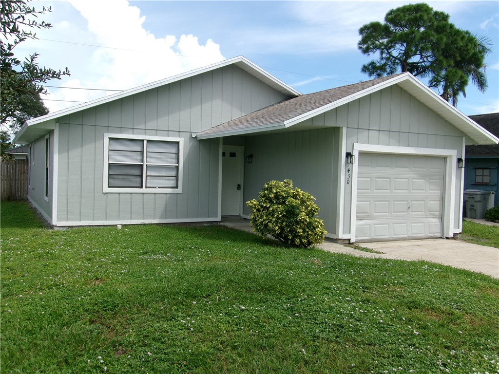 Light gray exterior siding with white trim, a single-car garage, and a front lawn with established plantings