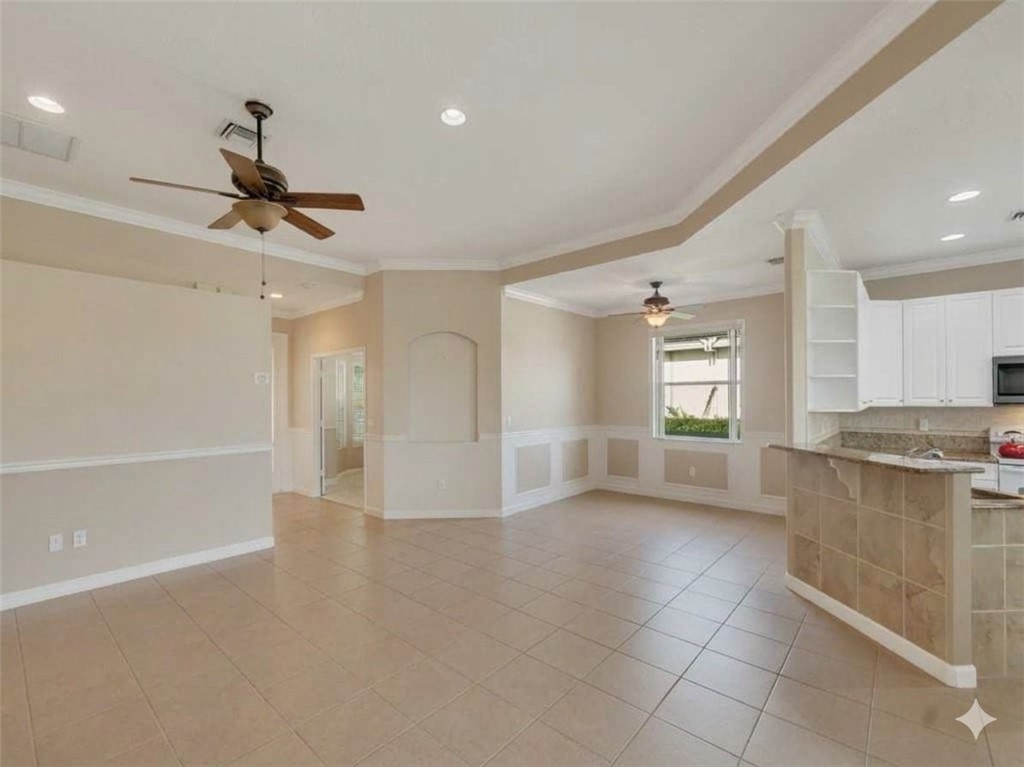 Porcelain tile flooring, white kitchen cabinetry, recessed lighting, ceiling fans, and a tiled kitchen island with a stone countertop