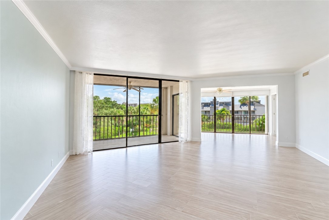 Expansive living area with light-toned wood-finish flooring and crown molding