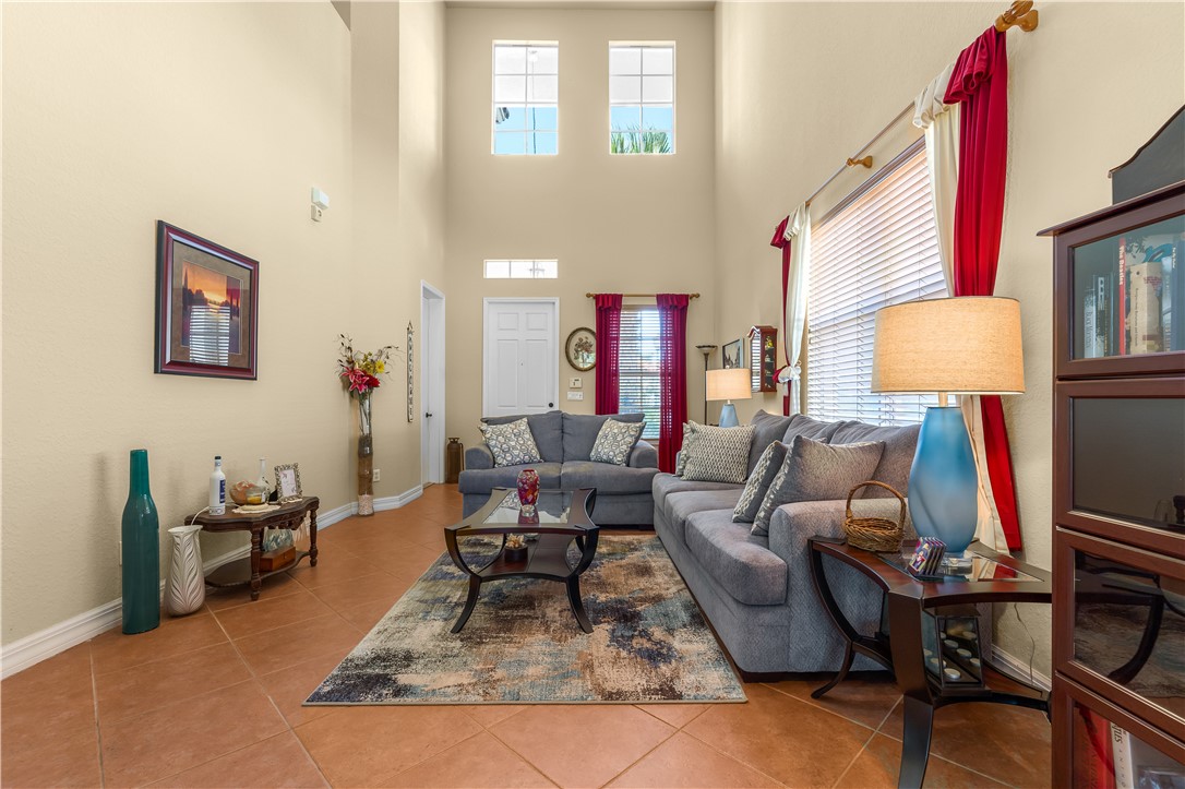Vaulted ceiling with high windows, main-level front entry door, large-format tile flooring, and a transom window
