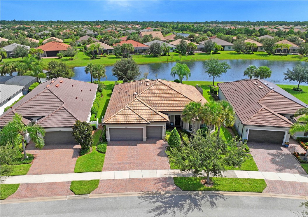 Residential property with tile roofing, paver driveway, and a well-maintained lawn