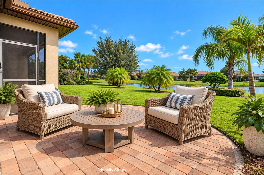 Virtually staged - Paver patio with a screened enclosure, expansive green space, mature palm trees, and water feature