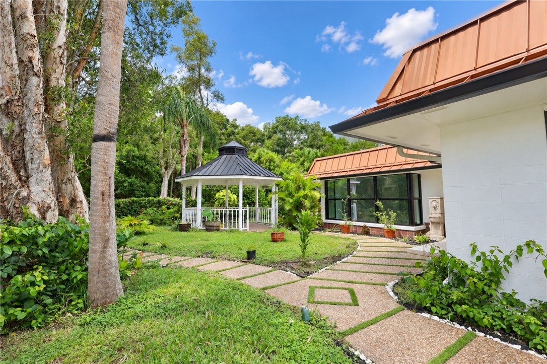 Manicured lawn with a white gazebo, a stone pathway, and mature trees