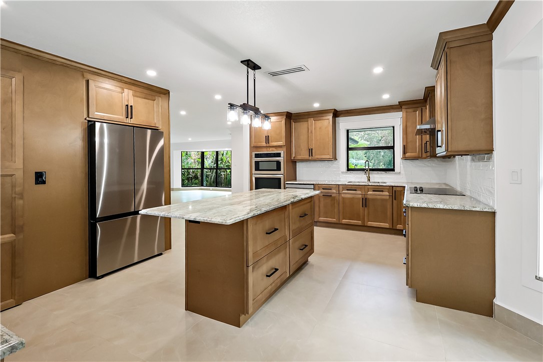 Kitchen featuring light wood-tone cabinetry, stainless steel appliances, a center island with a light-toned countertop, and recessed lighting