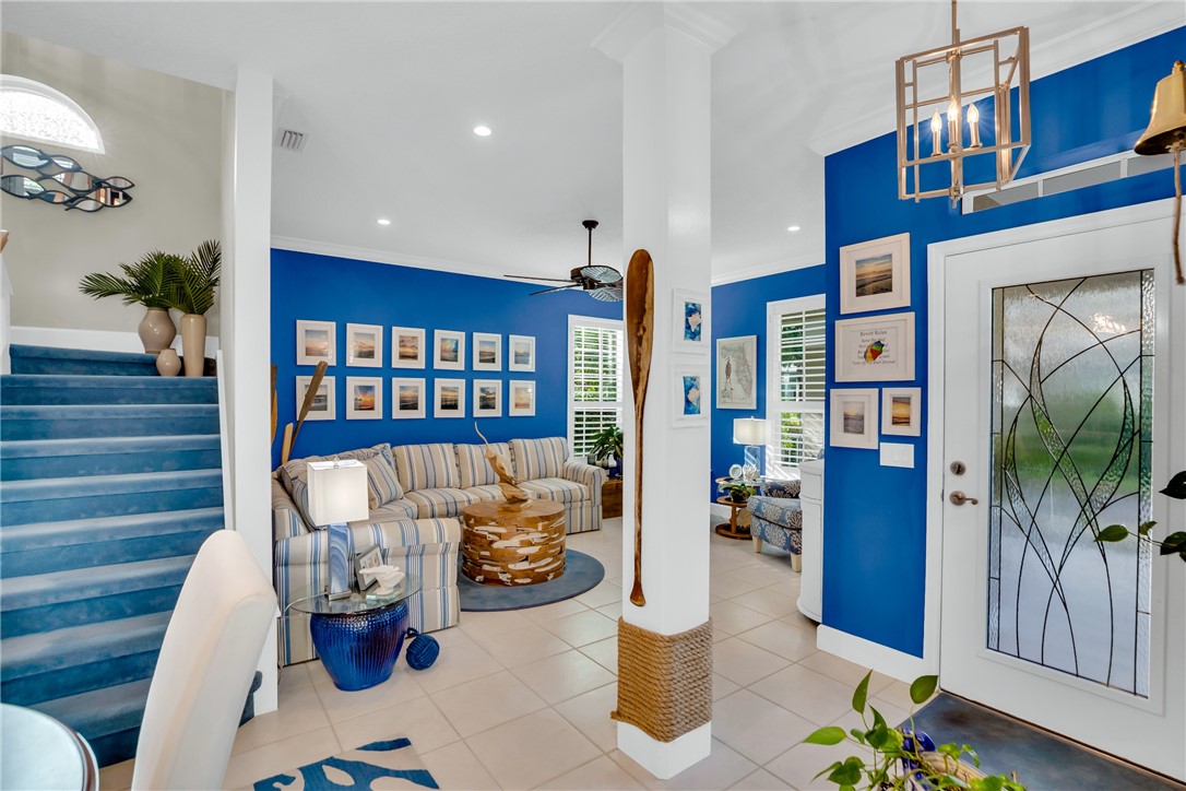 Tiled flooring, white entry door with decorative glass, recessed lighting, ceiling fan, and staircase with carpeted treads