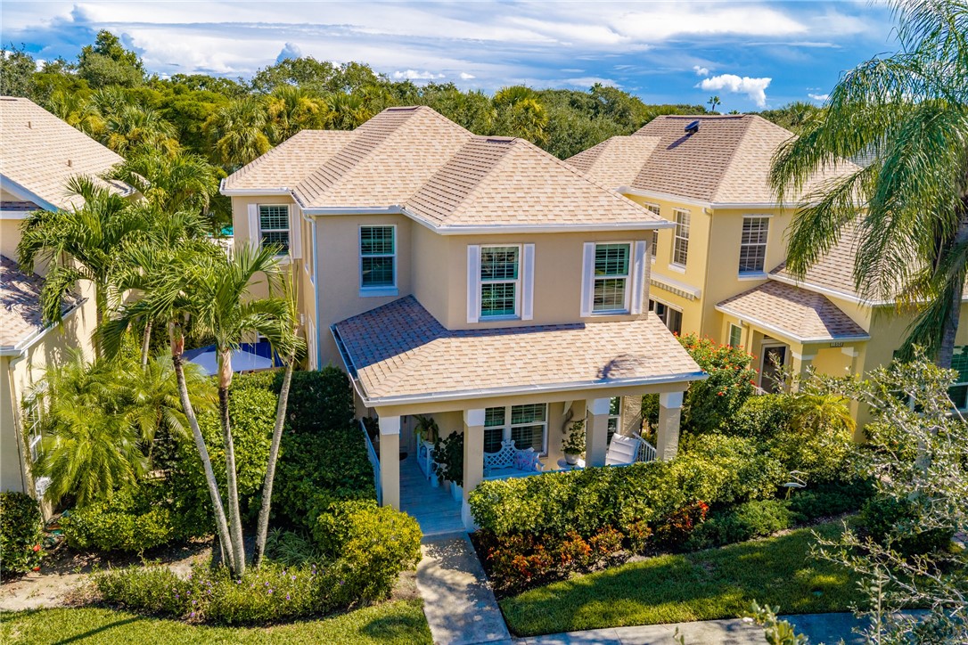 Two-story residence featuring a covered front porch, light-toned exterior, and shuttered windows