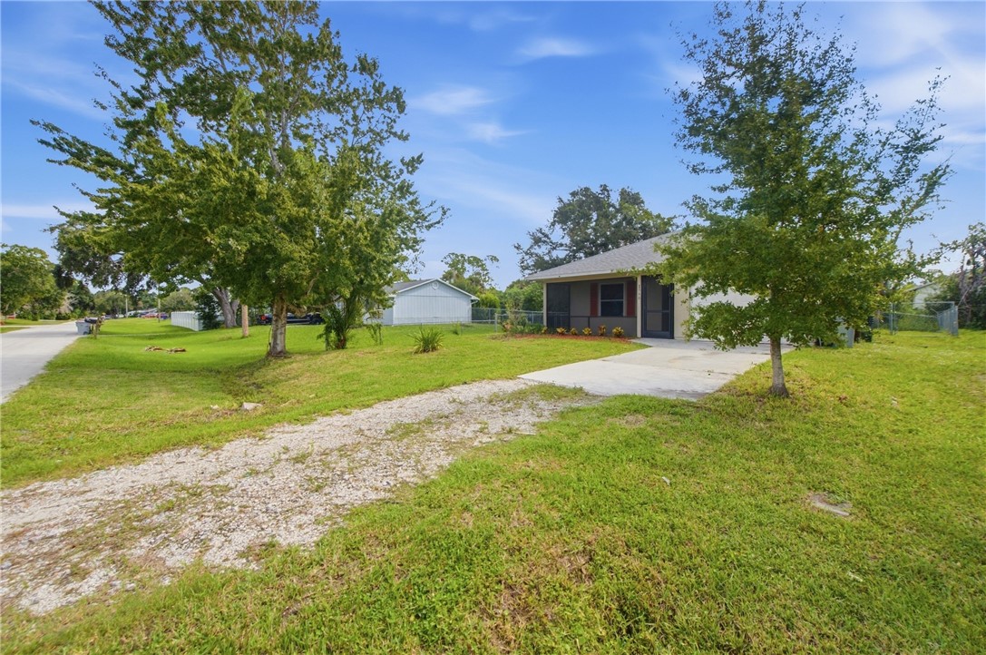 Single-story residence featuring a screened front porch, concrete driveway, and gravel driveway