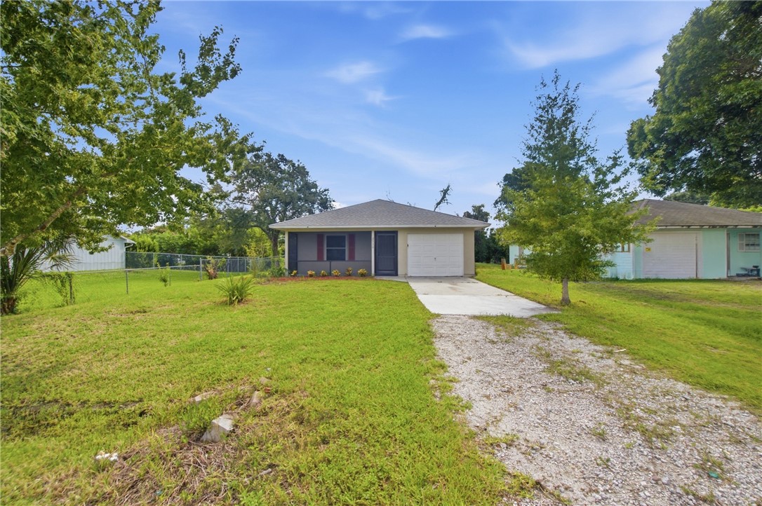 Single-story residence featuring a covered entry, attached garage, and a gravel driveway