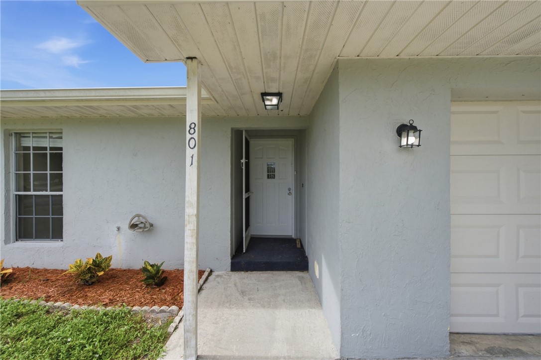 Stucco exterior with a covered entry, white paneled garage door, and decorative exterior lighting