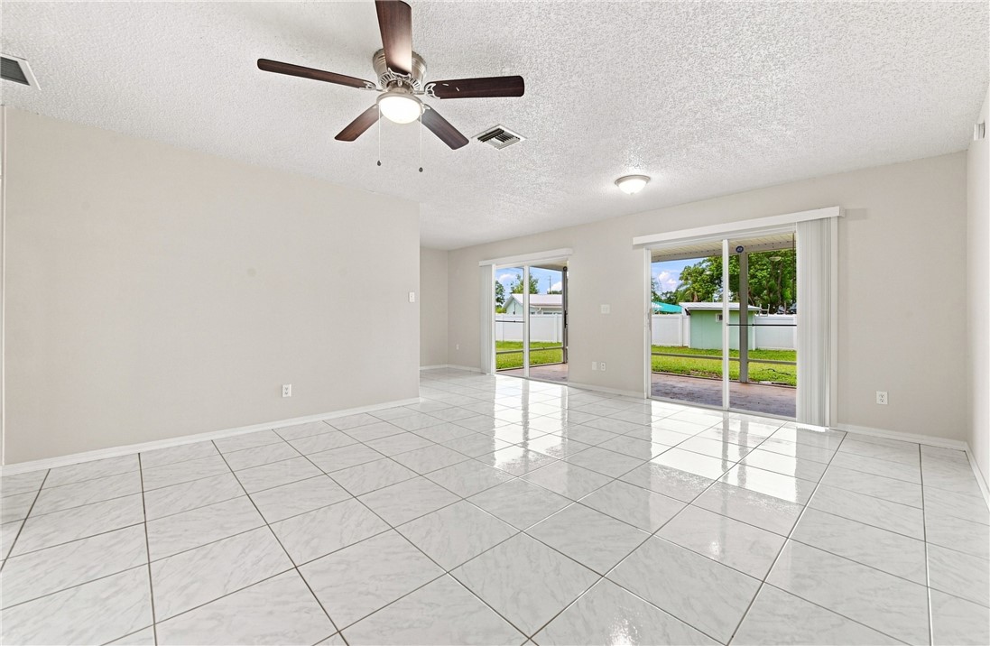Tile flooring throughout, two sets of glass sliding doors, and a ceiling fan with integrated lighting