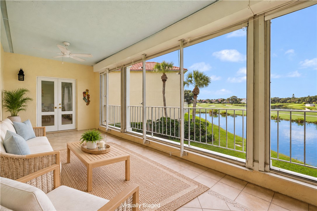 Enclosed lanai with tile flooring, ceiling fan, and double French doors, offering expansive golf course and water scenery