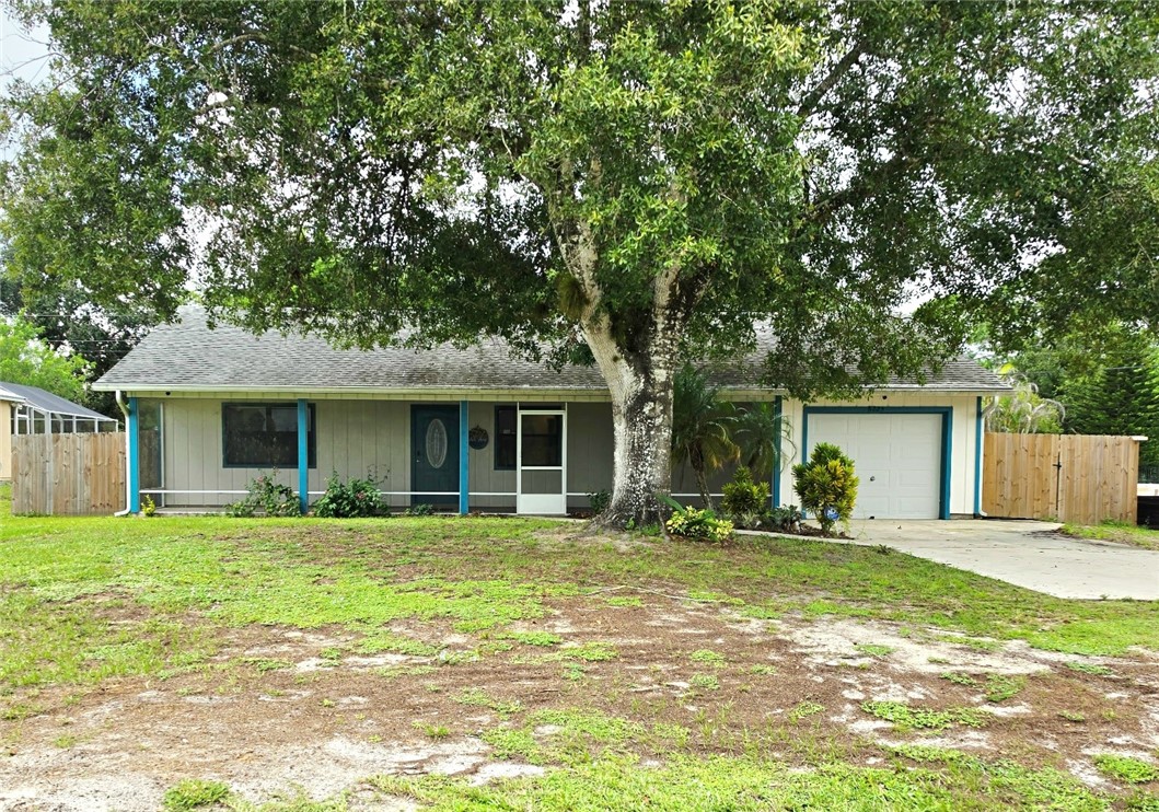 Single-story residence featuring a partial front porch with decorative columns, an attached single-car garage, and a screened entry