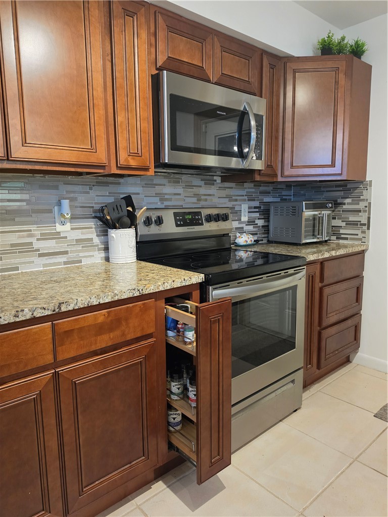 Wood-finish cabinetry with a tile backsplash and granite countertops