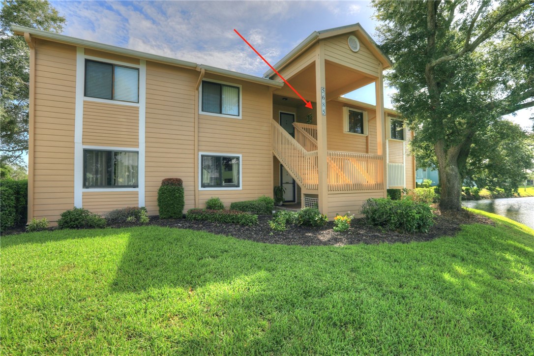 Two-story building exterior with horizontal siding, covered entry, and an exterior staircase