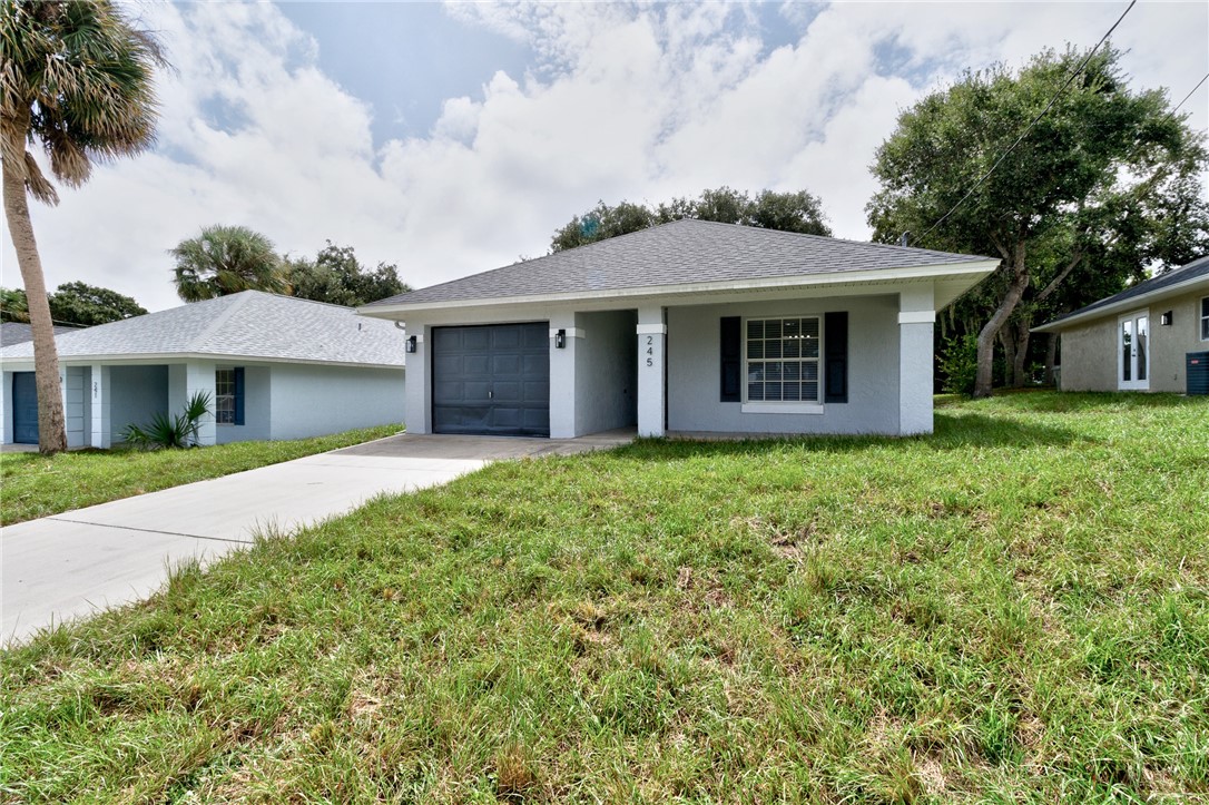 Single-story residence featuring a gray exterior, dark gray garage door, and a concrete driveway