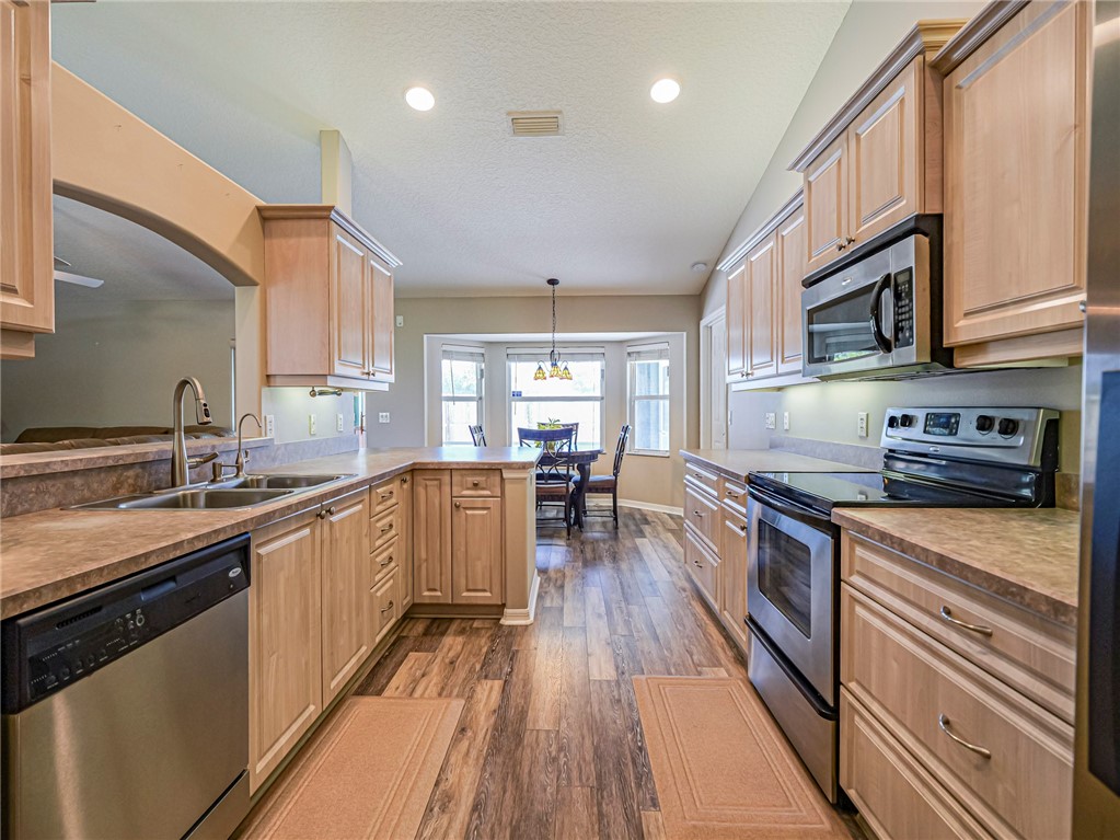 Full kitchen featuring wood-finish flooring, light wood cabinetry, stainless steel appliances, and recessed lighting