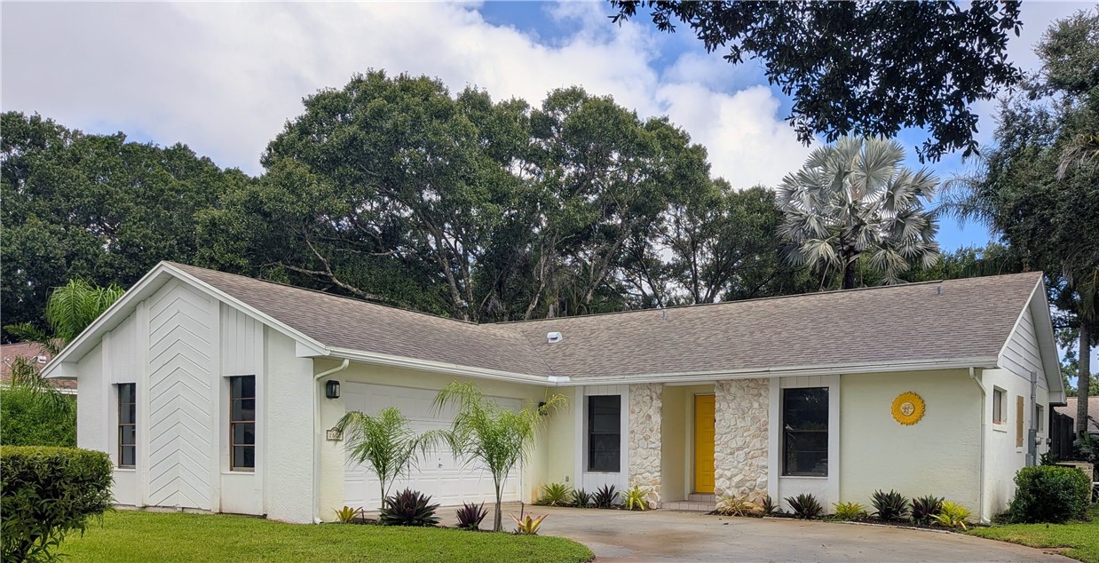 Single-story residence featuring a two-car garage, stone facade accent, and a brightly colored entry door