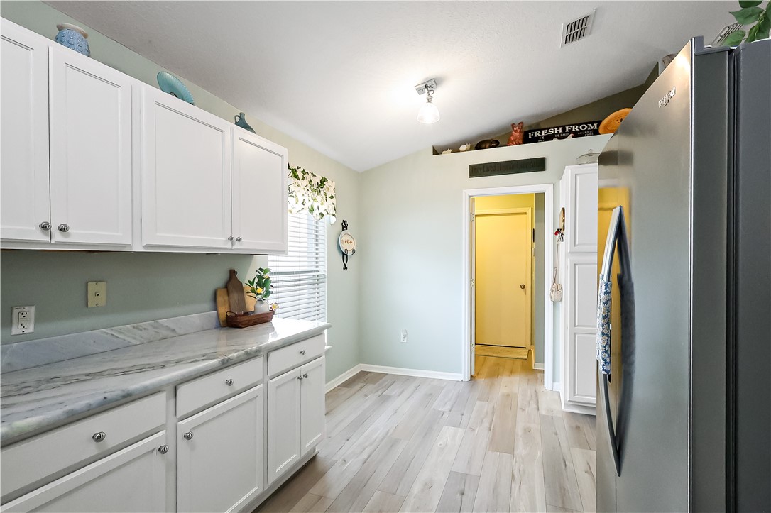 White cabinetry, light wood-finish flooring, light-colored countertops, and recessed lighting