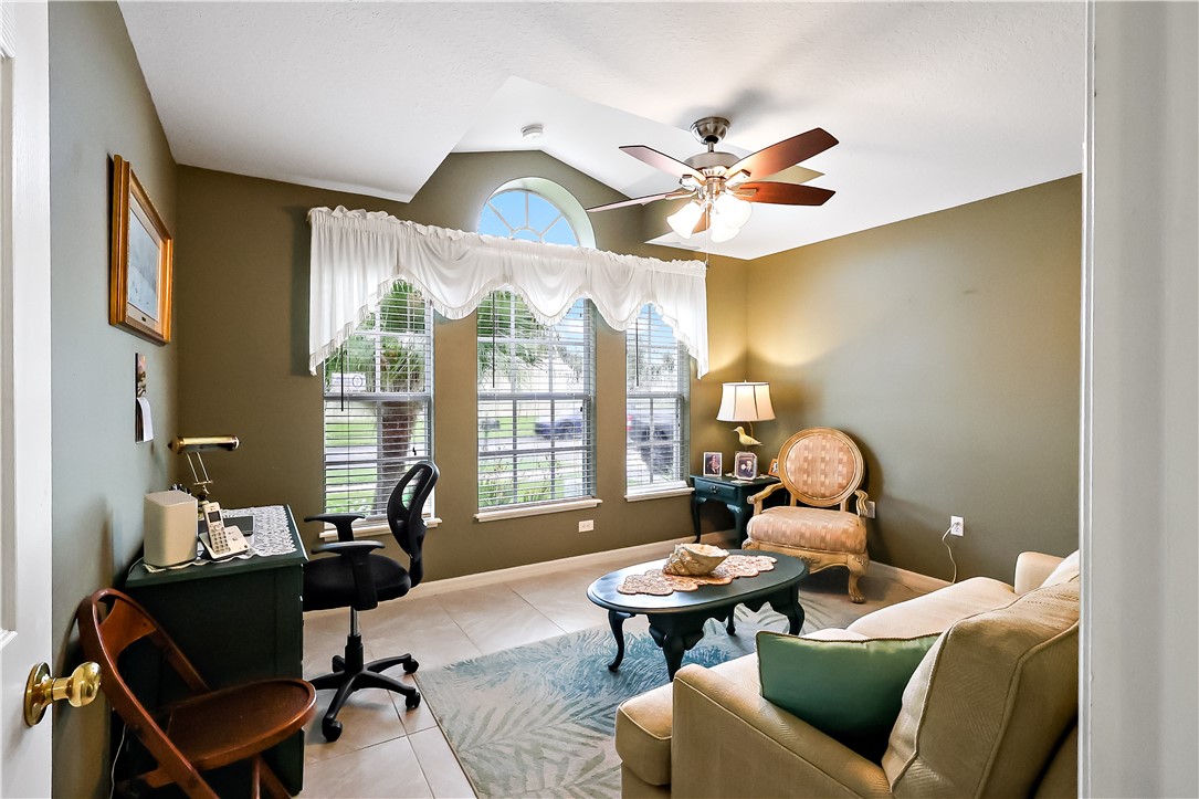 Vaulted ceiling with an arched window, ceiling fan with light fixture, and tile flooring