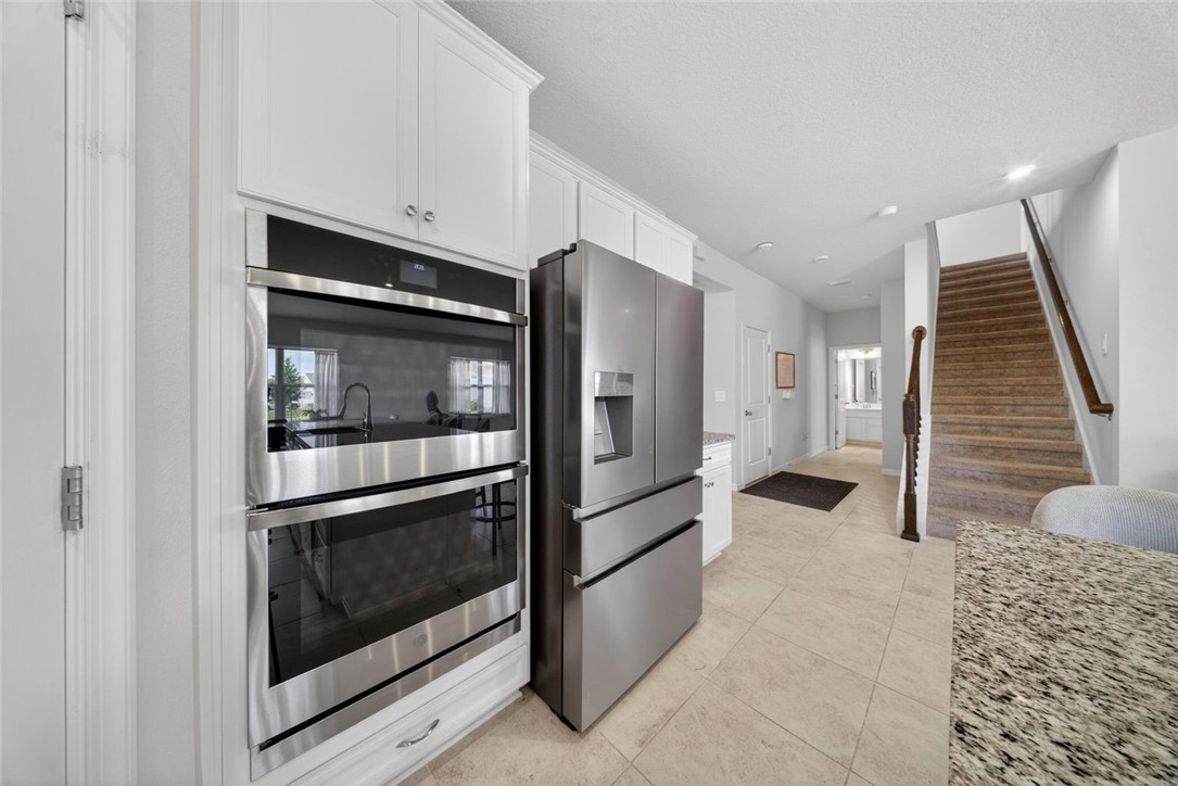 Stainless steel double wall ovens integrated into white cabinetry with crown molding