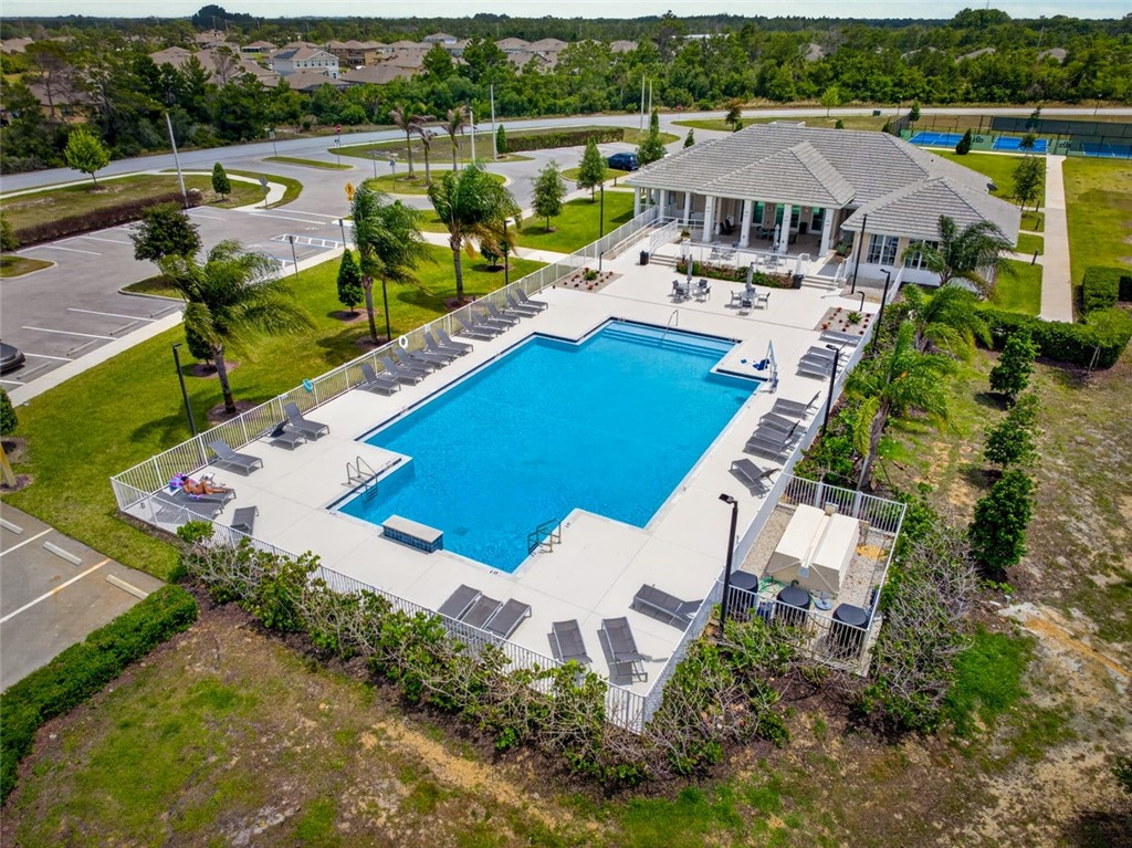 Expansive outdoor pool area featuring a rectangular swimming pool, surrounding lounge seating, and a paved sundeck