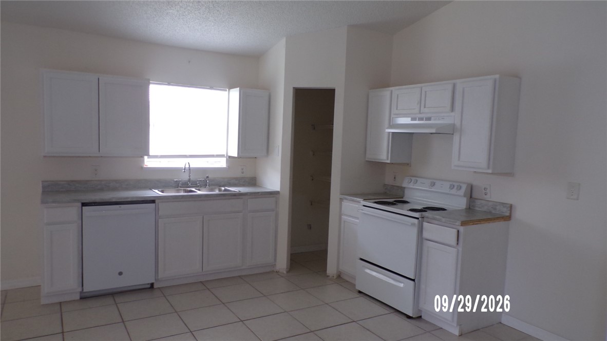 Kitchen featuring white cabinetry, tile flooring, and a window above the sink