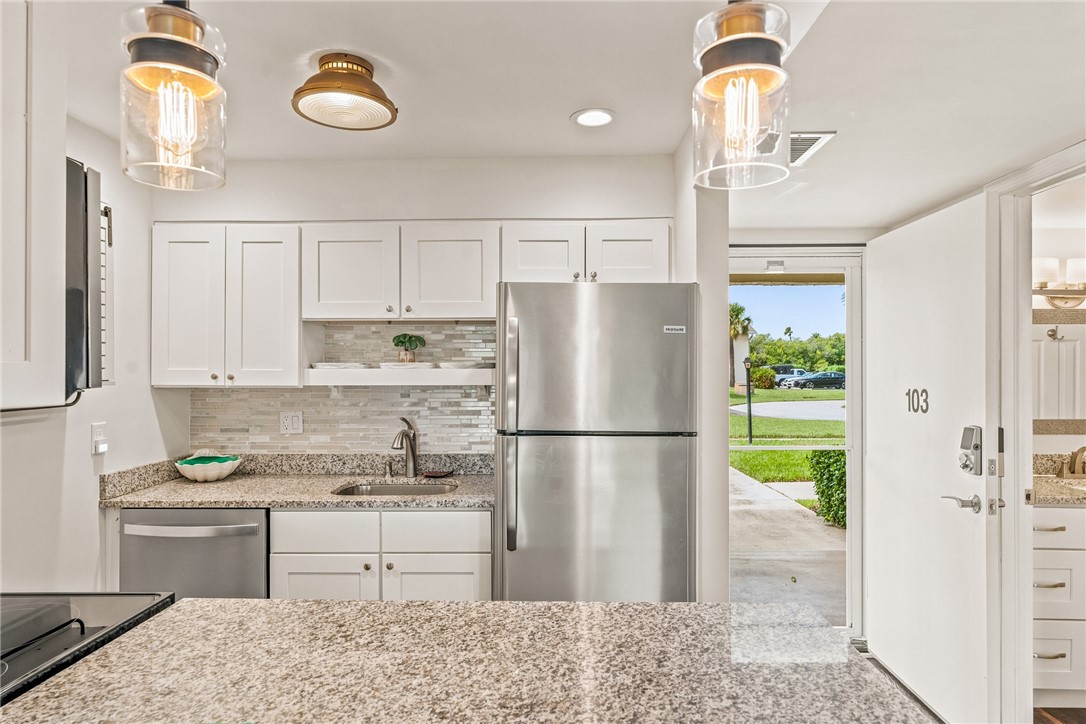 Kitchen featuring white shaker-style cabinetry, a tile backsplash, and granite countertops