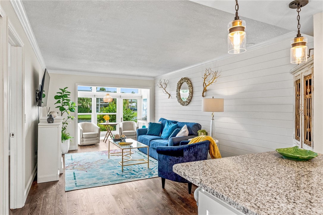 Wood-finish flooring, crown molding, white shiplap accent wall, white cabinetry, and granite countertop