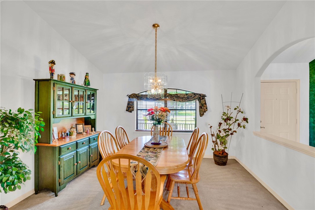 Spacious dining area featuring vaulted ceilings, an arched doorway, and a prominent window