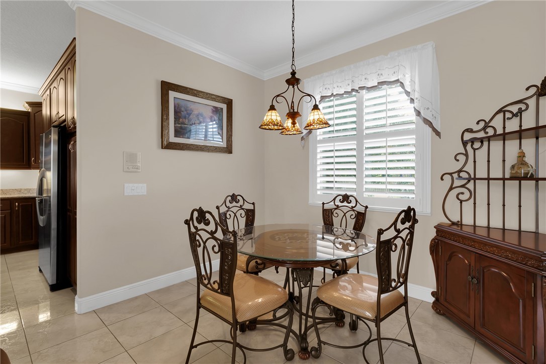 Crown molding accents, tile flooring, and a kitchen with dark wood cabinetry and stainless steel appliances