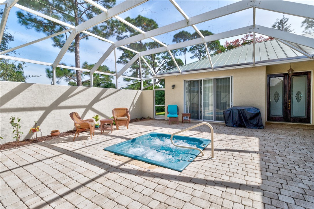 Screened outdoor living area with an in-ground spa, paver patio, and sliding glass doors