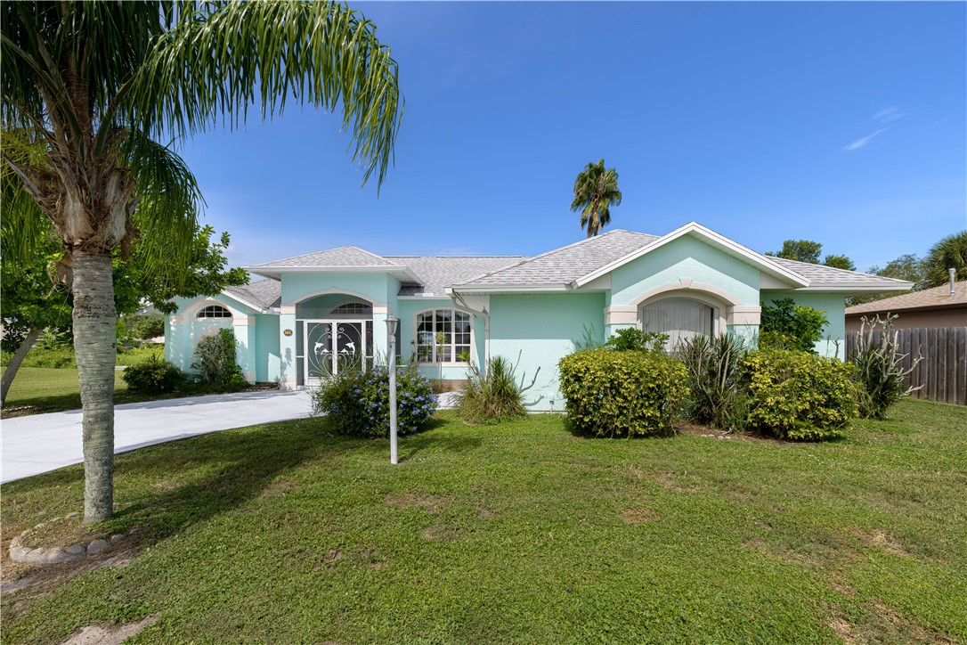 Single-story residence featuring a light blue exterior, arched windows, and a driveway