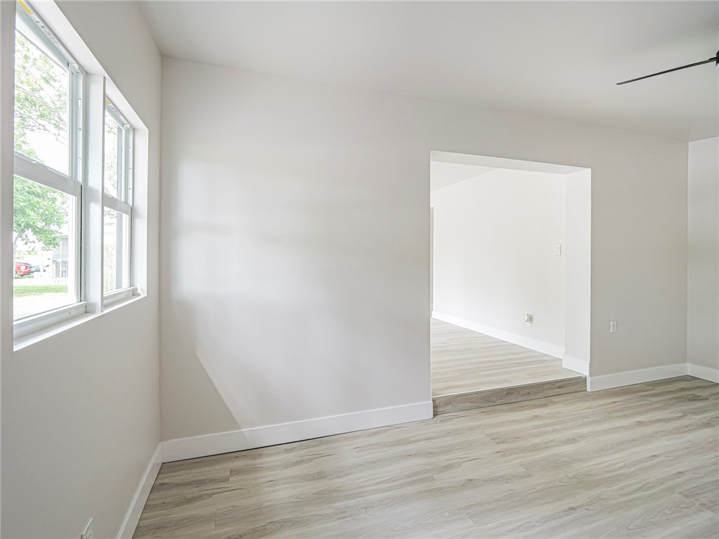 Light-toned wood-finish flooring, white painted walls, and a ceiling fan