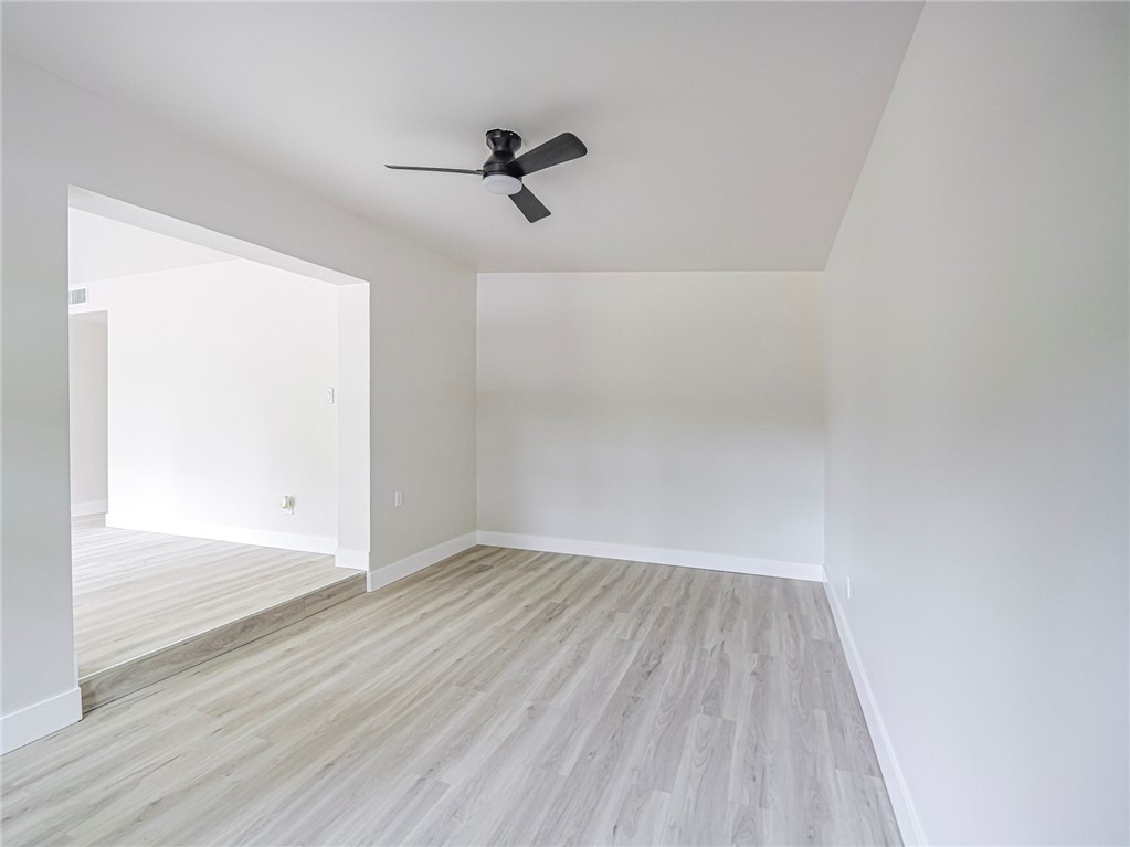 Recessed archway, wood-finish flooring, ceiling fan with integrated lighting, white walls, and white trim